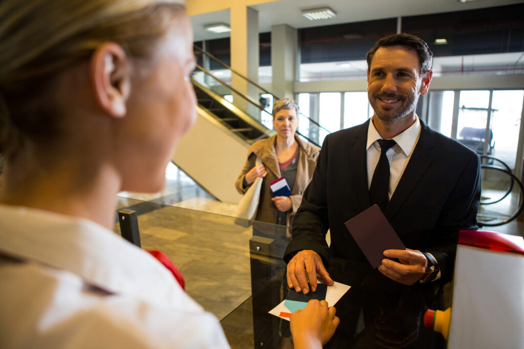 Female staff giving boarding pass to the passenger at the check in desk